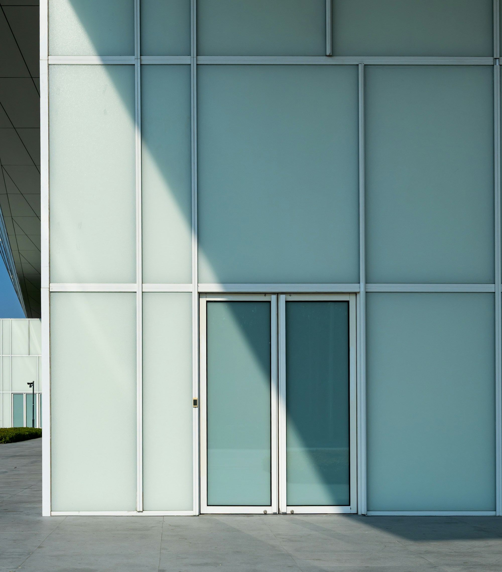 A pale glass wall with a glass door set into it, almost no frame in sight.